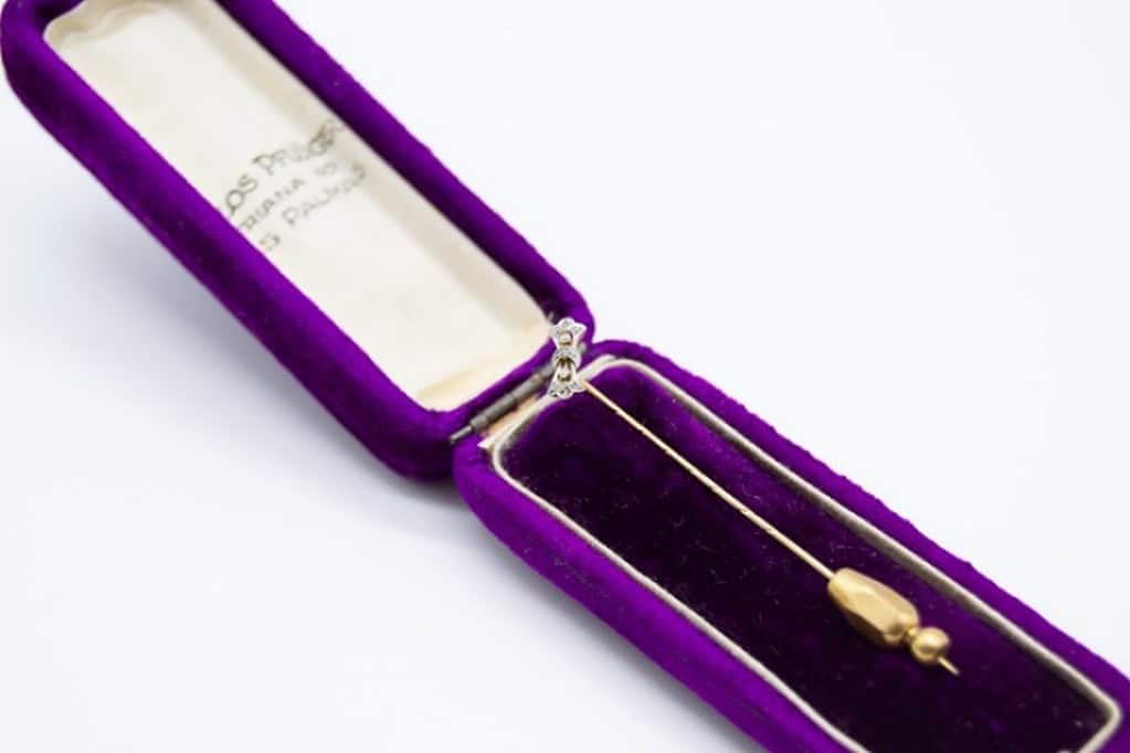 Broche de oro en estuche de terciopelo morado.