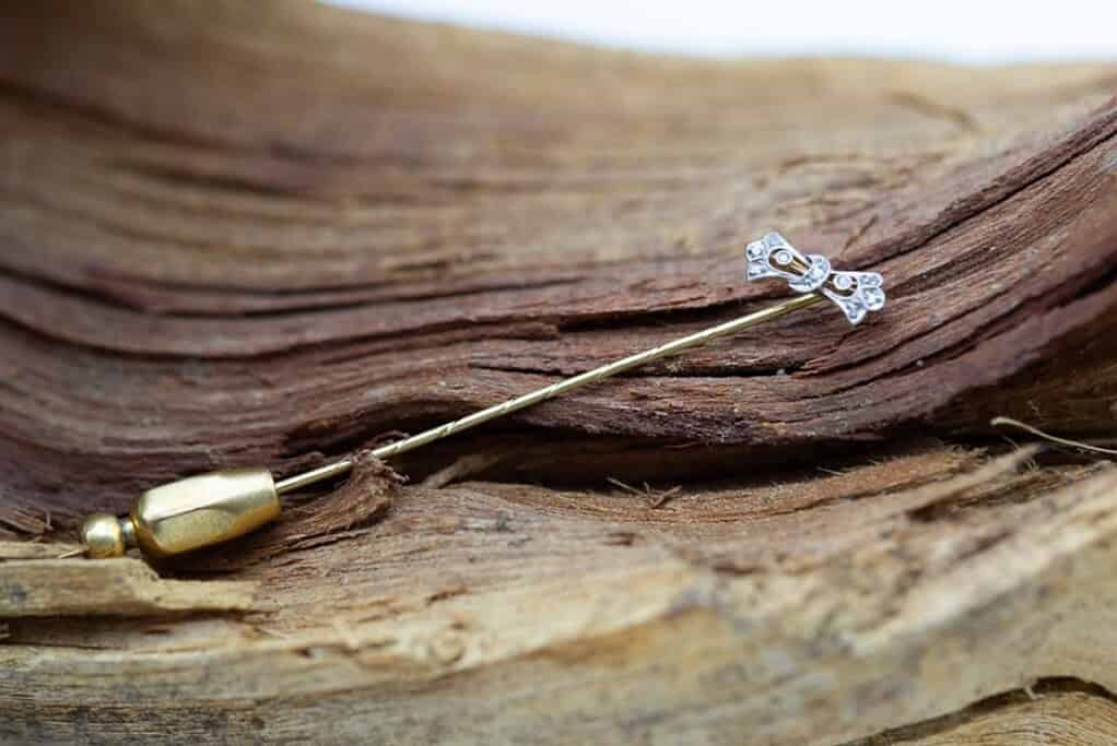 Broche de oro y plata en madera, símbolo de artesanía y elegancia en joyería.