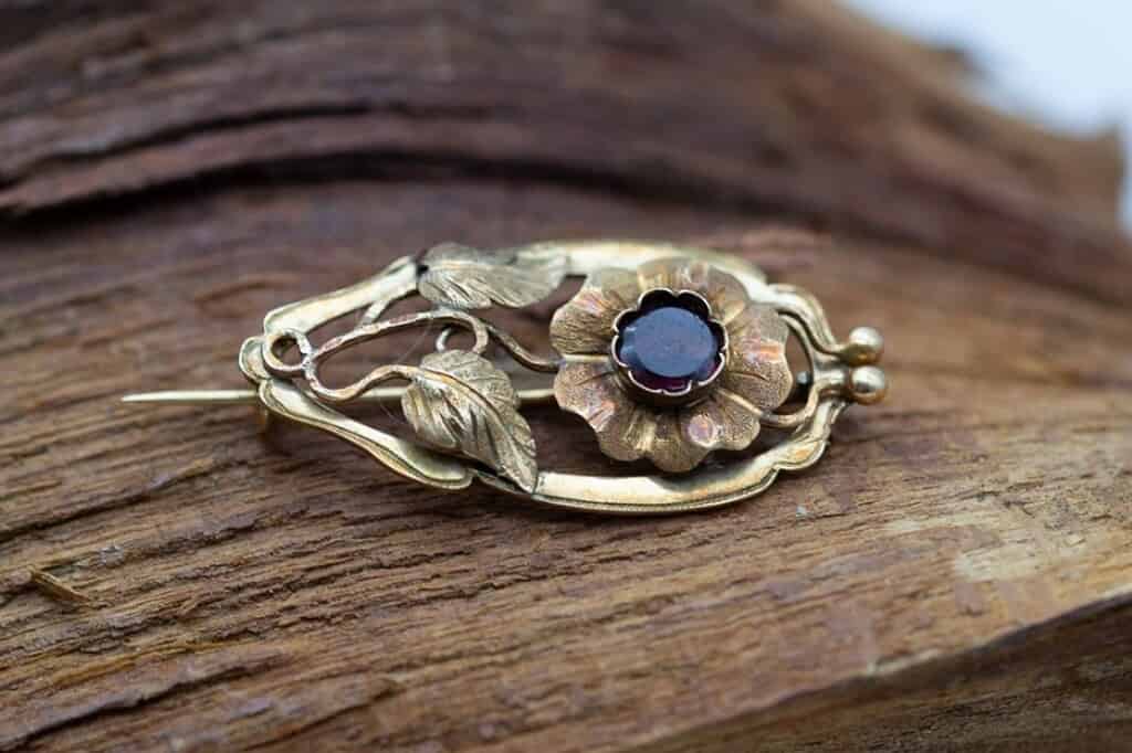Broche de oro con motivo floral y una gema.