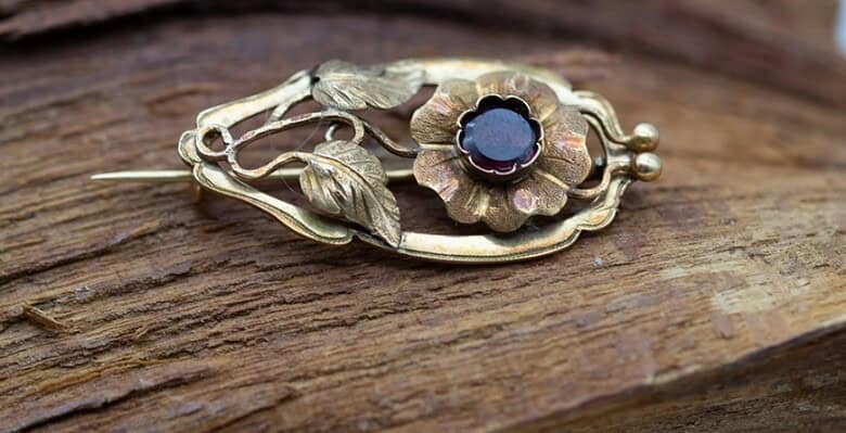 Broche de oro con motivo floral y una gema.