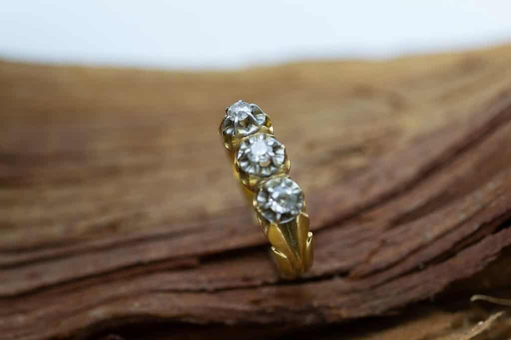Sortija de oro con diamantes sobre madera.